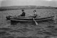 David and his Dad, each in a rowing
                boat, on a wide stretch of water with hills in the
                distance